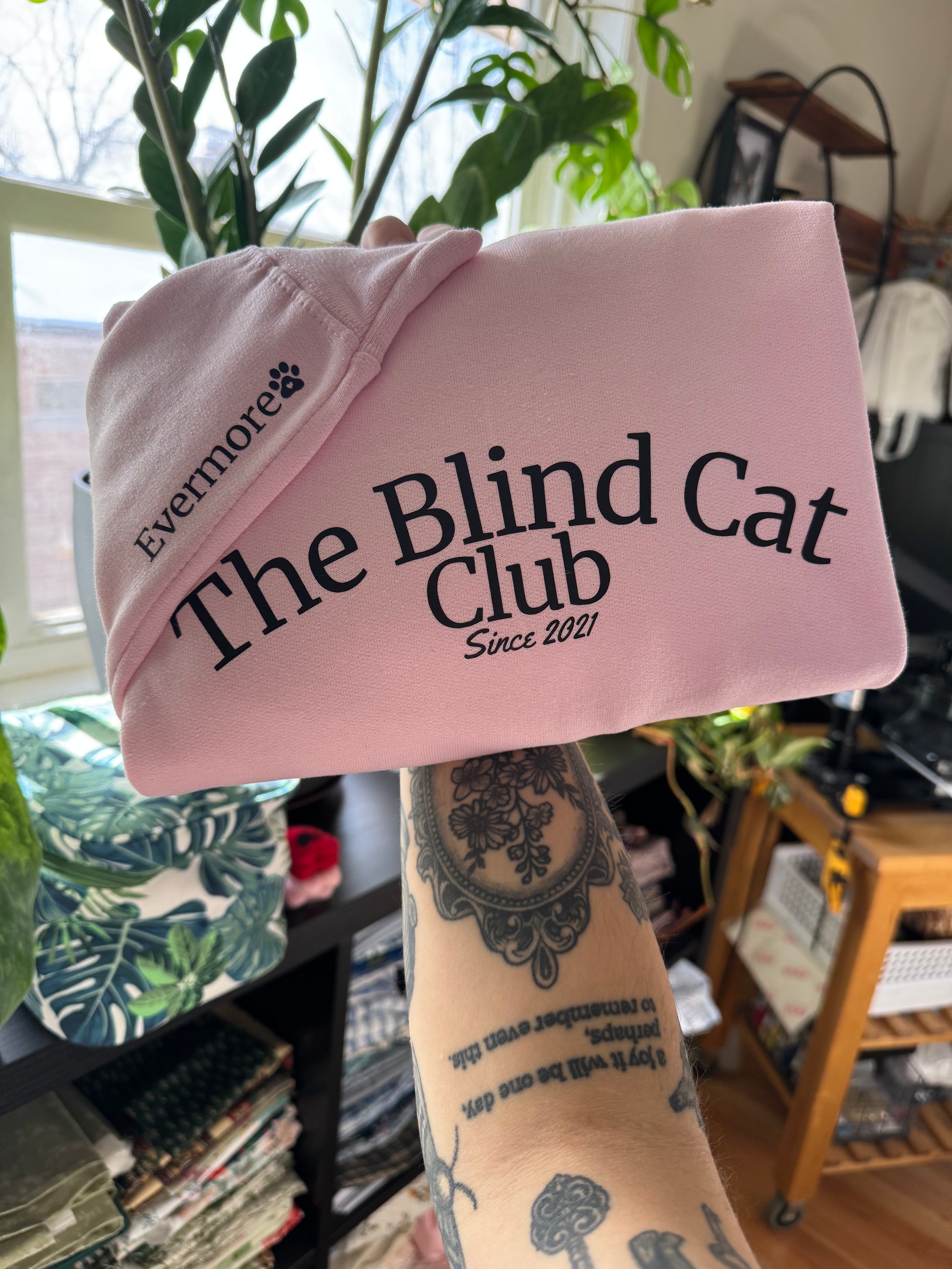 Folded pink crewneck sweatshirt with example of customizable pet name on sleeve