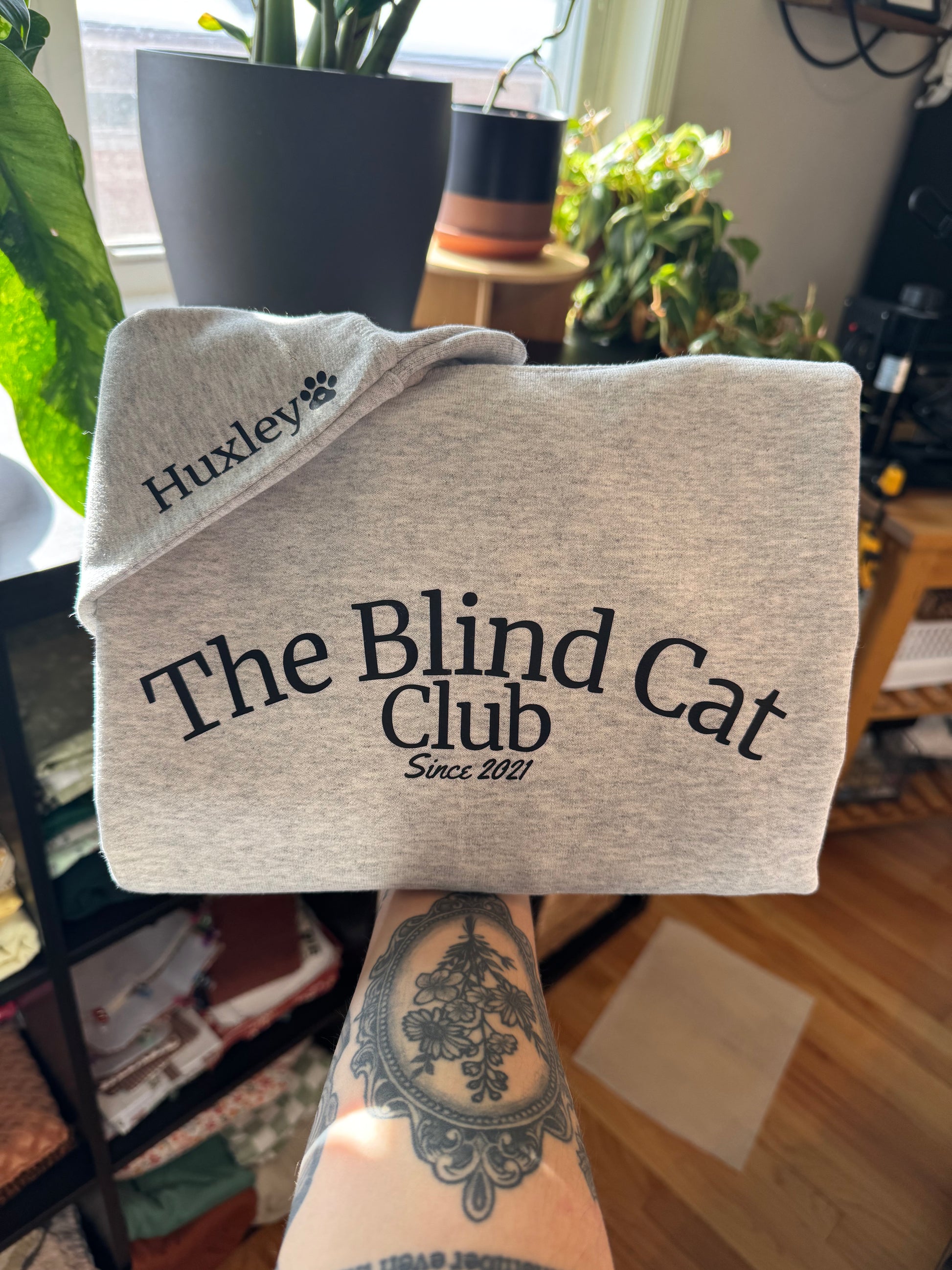 Folded grey crewneck sweatshirt with example of customizable pet name on sleeve