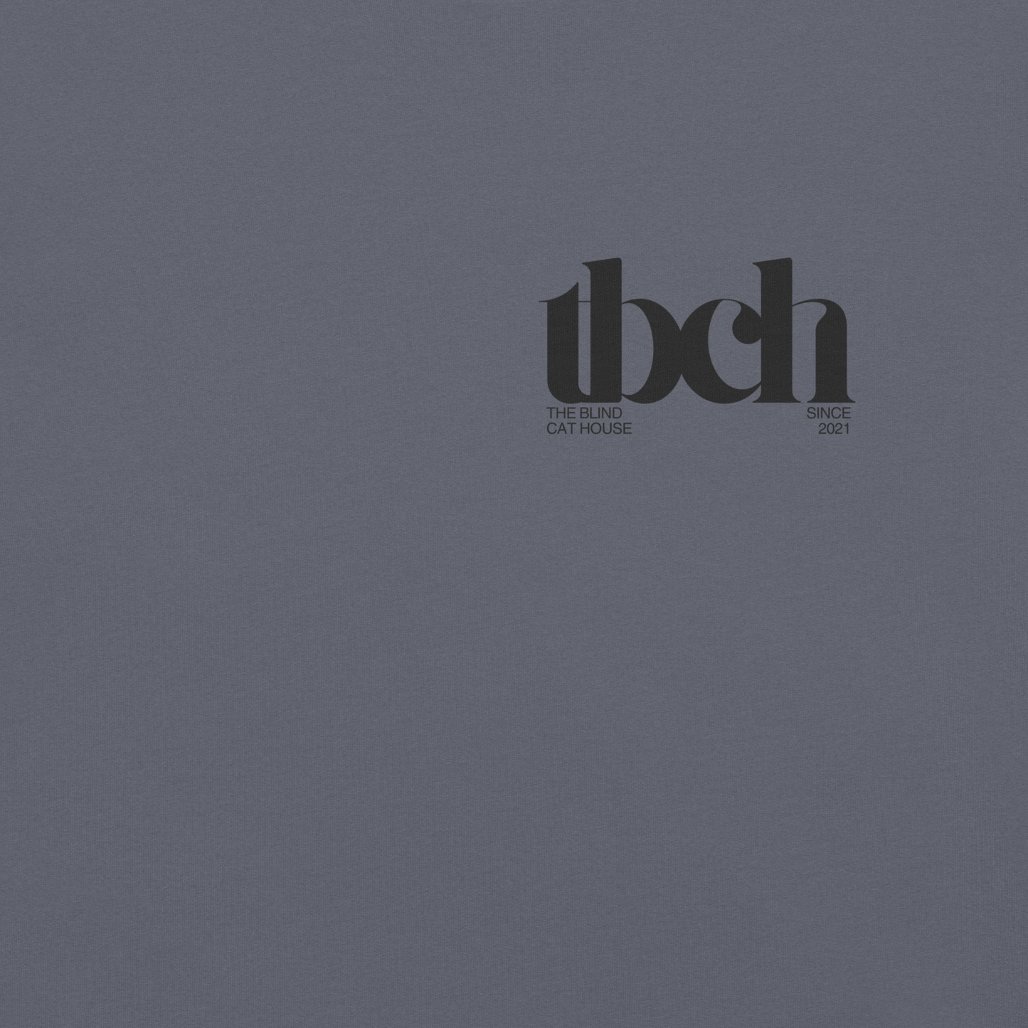 Vintage-style typography text reading 'tbch' on the front right corner of a denim colored fabric